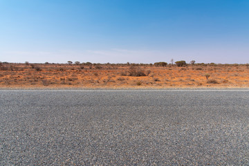 The road view with red dirt at the background and blue sky at outback rural of New South wales,...