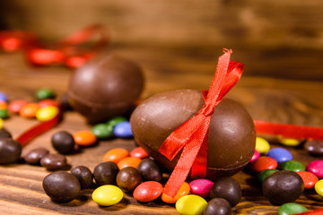 Chocolate easter eggs and multicolored candies on wooden table