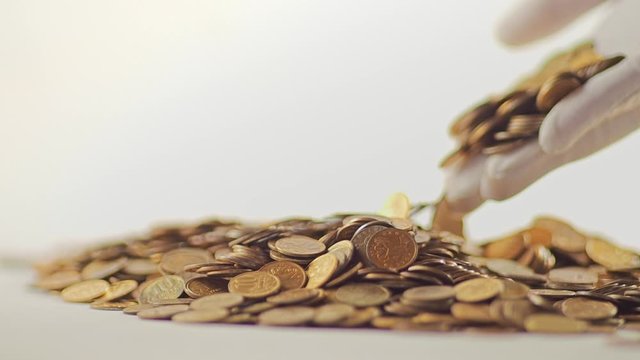White-gloved hands scooping up a pile of gold coins. They sort out and scatter money.On white background. Garland. Money glitters.