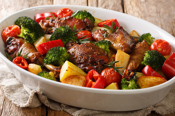 Sliced chicken with baked potatoes, broccoli, tomatoes and bell pepper close-up in a baking dish on the table. horizontal