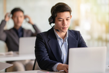 Young handsome male customer support phone operator with headset working in call center.