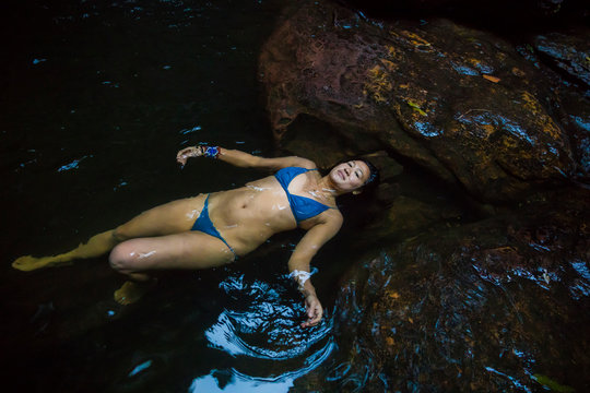 Beautiful Asian female floating in natural water hole, Empress Falls, Blue Mountains National Park