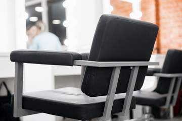 Fototapeta na wymiar Black chair for client, blurred background beauty salon, master makeup artist workplace