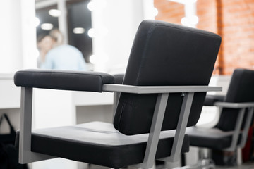Black chair for client, blurred background beauty salon, master makeup artist workplace