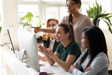 Diverse women coworkers look at computer discuss new common project