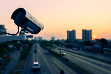 CCTV, Surveillance camera operating in city watching traffic road at sunset