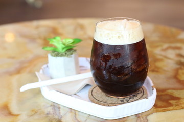 Black coffee with ice on table in cafe.