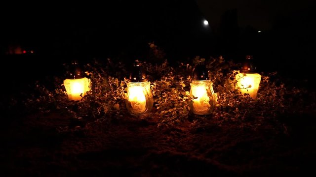 Grave candles in the dark night at the cemetery all souls day