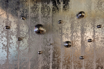 iron balls of various shapes hanging randomly on a gray wall 