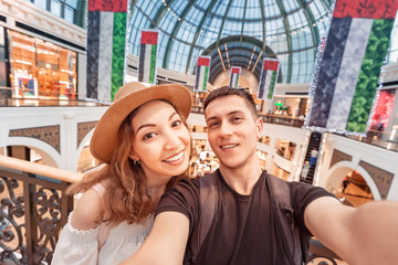 Fototapeta na wymiar A couple in love - Asian girl and a European man take a selfie in a shopping Mall in the United Arab Emirates. Holidays and entertainment in Dubai