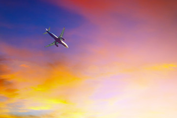 Passenger plane flying in colorful sky at sunset