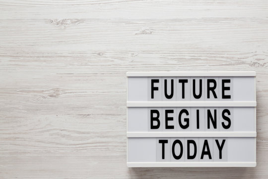 'Future begins today' words on a modern board on a white wooden background, top view. Overhead, from above, flat lay. Copy space.