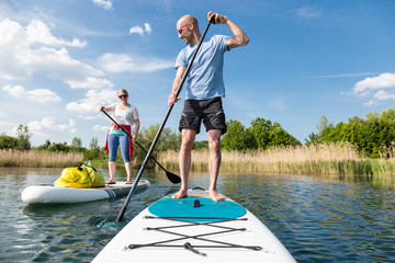 Couple on stand up paddle board on the lake, SUP - obrazy, fototapety, plakaty