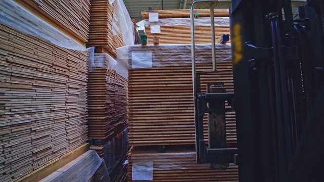 Woodworking industry. Forklift cart putting stack of wooden boards on the floor. Modern factory of wood production. Camera motion back.
