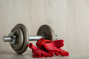 Iron dumbbell and fitness glove on a wooden floor