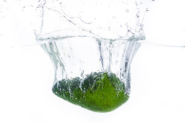 A Avocado splashing into water against a white background