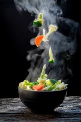 Store enrouleur sans perçage Manger La vapeur des légumes carotte brocoli chou-fleur sur bol noir, une cuisson à la vapeur. Nourriture saine chaude bouillie sur table sur fond noir, nourriture chaude et concept de repas sain