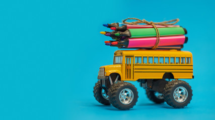 Yellow School bus and felt-tip pens on the roof, back to school concept, yellow background, copy space. education. isolated on blue background