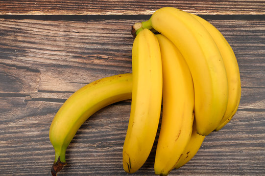 Bunch of ripe yellow bananas on a wooden background. Close up.
