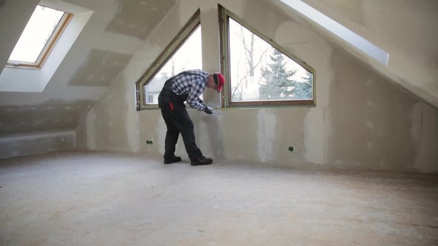handyman making measurements for window sill for new installed pvc windows in a new build attic