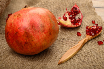 Ripe juicy pomegranate, pieces of pomegranate and pomegranate seeds in a wooden spoon on a...
