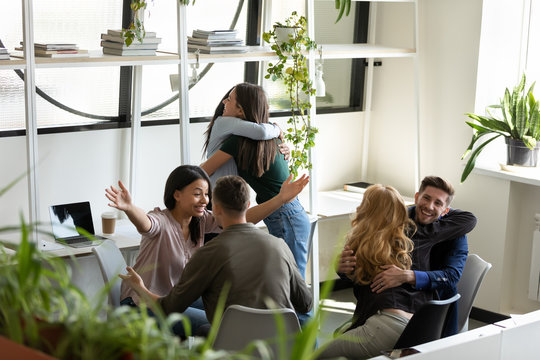 Multiracial colleagues hugging congratulating each other with common department success
