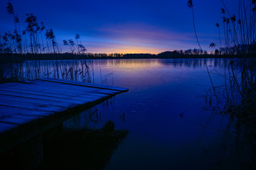 Fototapeta premium sunrise over wooden jetty and frozen lake