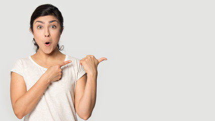 Excited millennial indian ethnicity lady pointing fingers aside on copyspace.