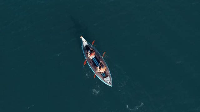 Aerial view drone happy mother and son rowing in inflatable kayak on water of large lake with dog on background of picturesque cliffs, green vegetation, beautiful sunset day. Family sport. Lifestyle