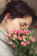 bouquet of bush of roses in female hands on a background of knitted sweaters