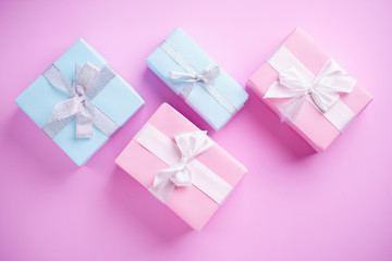 Presents, holiday traditions and shopping. Gift boxes in wrapping paper and tied with satin ribbon on pink background, copy space