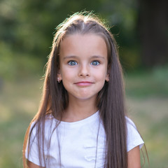 Surprise. Pretty funny little girl with long brown hair posing summer nature outdoor. Cute kid's portrait. Beautiful child's face. Facial expressions.