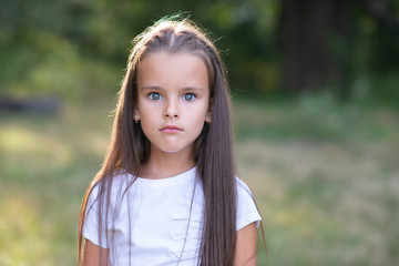 Surprise. Pretty funny little girl with long brown hair posing summer nature outdoor. Cute kid's portrait. Beautiful child's face. Facial expressions.