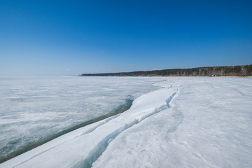 Frozen lake covered with ice. Winter landscape.
