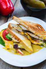 Classic breakfast, hot sandwiches with cheese, vegetables and chicken on a wooden table.