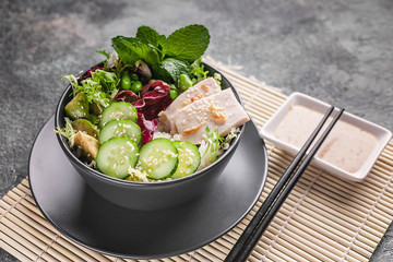 Asian food. Close up stir fry rice, vegetables and ham with nutty spicy sauce on a bamboo mat.
