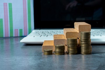 The concept of economic planning. Piles of coins, wooden blocks in the form of steps on the background of a PC keyboard. The idea of a career ladder for successful business development and fit growth