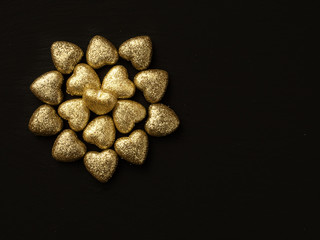 Fototapeta na wymiar Golden glitter covered hearts design on dark background. Saint Valentine theme. Copy space.