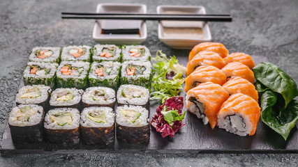 Asian food banner. Close up rolls with salmon and vegetables on a black stone board. Chinese cuisine.