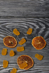 Obraz na płótnie Canvas Jelly chewing sweets. Dried slices of orange. Scattered on brushed pine boards painted in black and white.