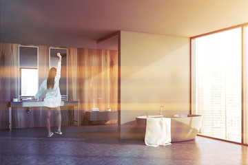 Woman in panoramic gray and wooden bathroom