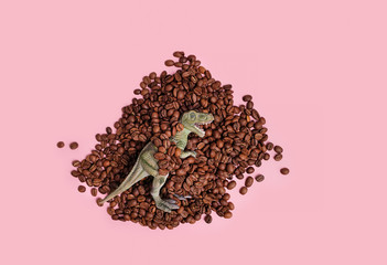 dinosaur toy and coffee beans on pink background. minimal creative concept. coffee beans, T-Rex...