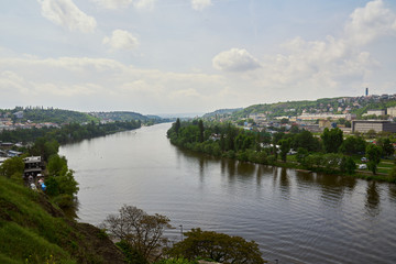 Obraz premium Top view of the wide Vltava river. Horizontal photo of colorful European city of Prague in Czech Republic daytime, cloudy sky, month of may, travel in tourist place.