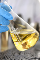 Male hands in protective gloves hold test tube in hands produces chemistry test of motor oil...