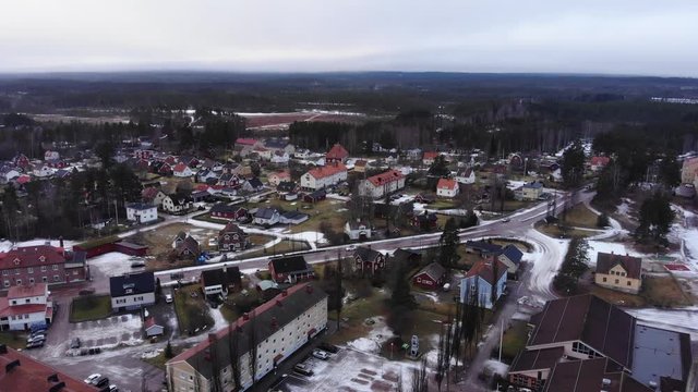 Drone slowly moving away from the small and calm town of Vansbro, Sweden. Some snow left on the ground, but mostly melting.