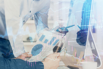 Double exposure of chart with businessman typing on computer in office on background. Concept of hard work.