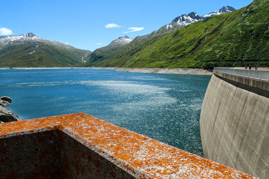 Picture from the Santa Maria Dam at Luckmanierpass in Switzerland. The day is hot and sunny, the water and sky are blue. The nature is beautiful. 