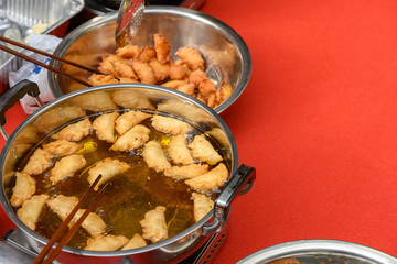 deep frying traditional Chinese Yau Kok Zai or sweet dumpling with some raw ones nearby for Chinese New Year