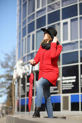 Fototapeta na wymiar Pretty girl on a walk in red coat in the city