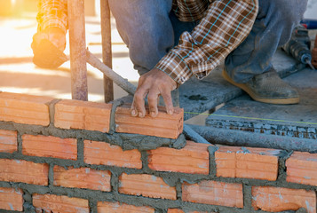 Close up of industrial bricklayer installing bricks on construction site